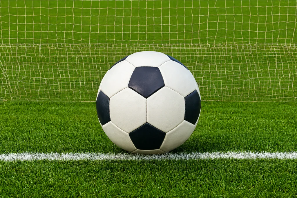 Goal net and the back of the net photographed from the goal line on a floodlit pitch