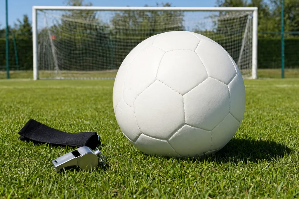 Referee coin, stopwatch and notebook arranged on the centre circle grass before kick off
