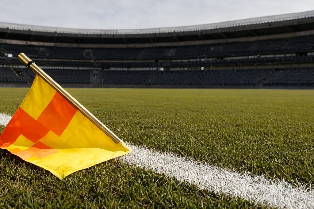 Assistant referee raising a flag on the far touchline of an empty stadium